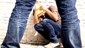 A young man with his hands up, cowering in front of a bully.